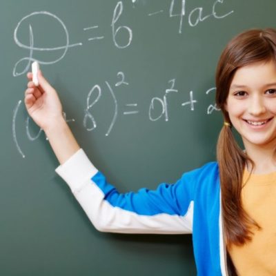Confident student pointing at formula on blackboard during algebra lesson
